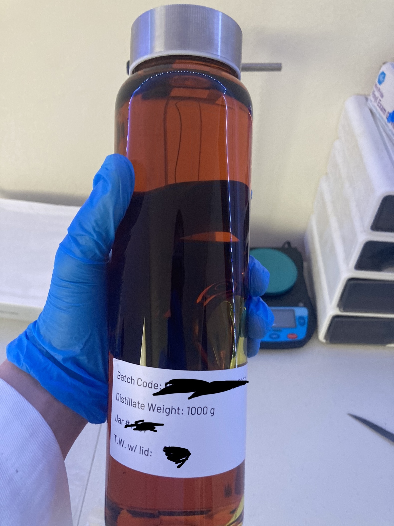 Sealed laboratory container labeled as 1000 grams of distillate